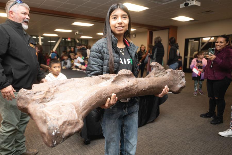 一名儿童学院的学生在能源学院的杜根地质博物馆里拿着一块化石!